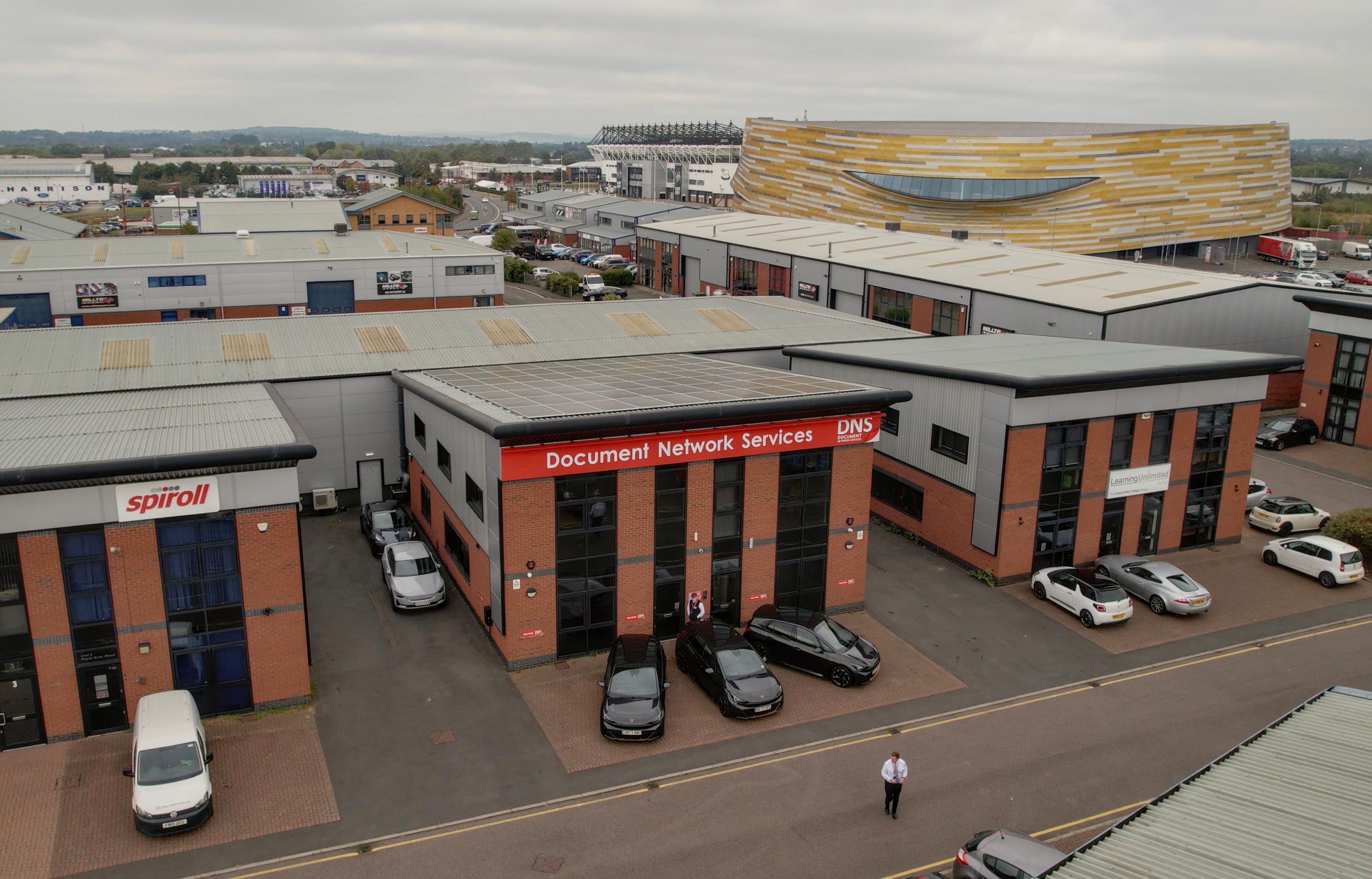 Aerial view of business units with a solar array on the flat roof of the central building.