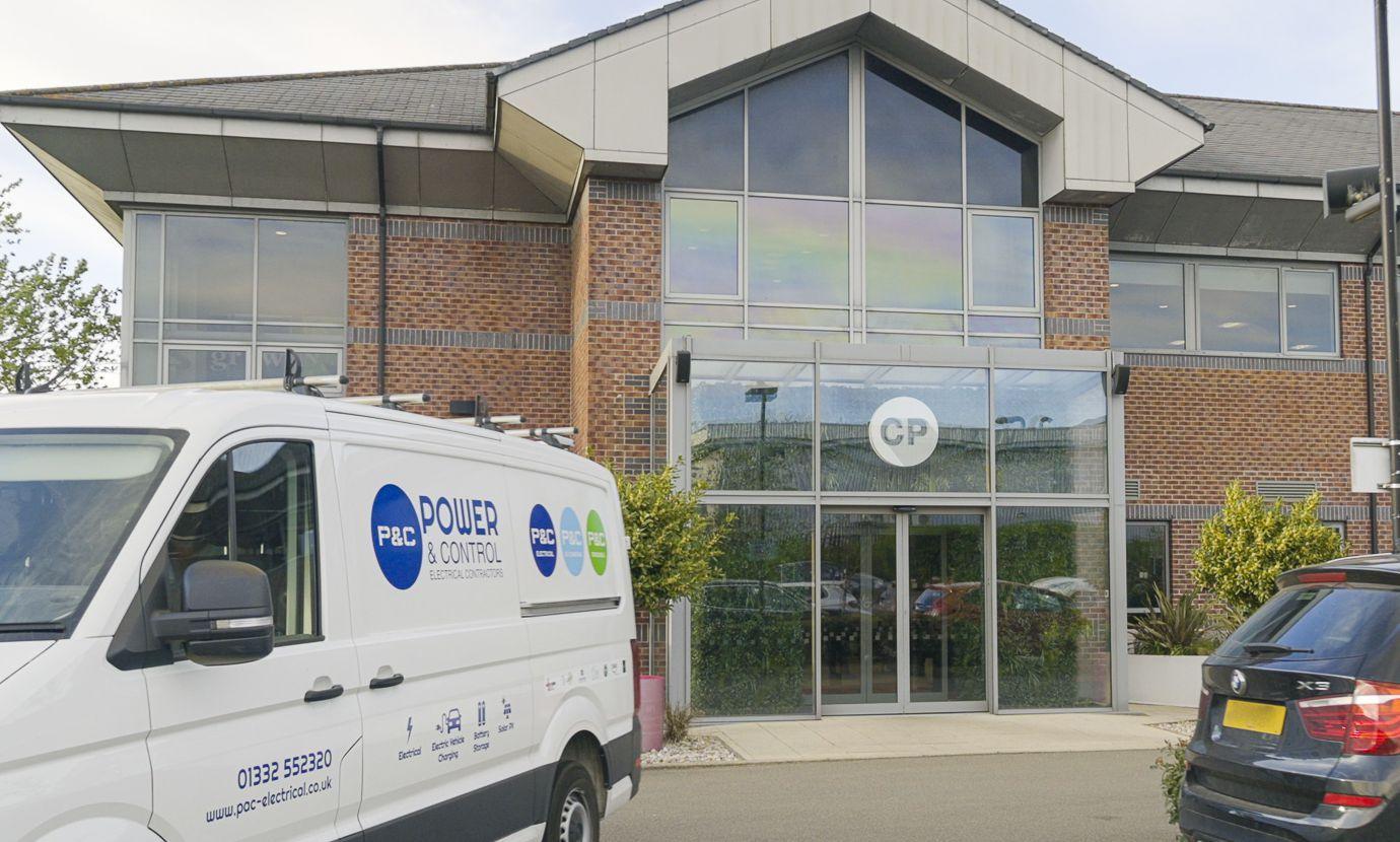 A P&C Electrical van parked outside the glazed entrance of the Cooper Parry office building.