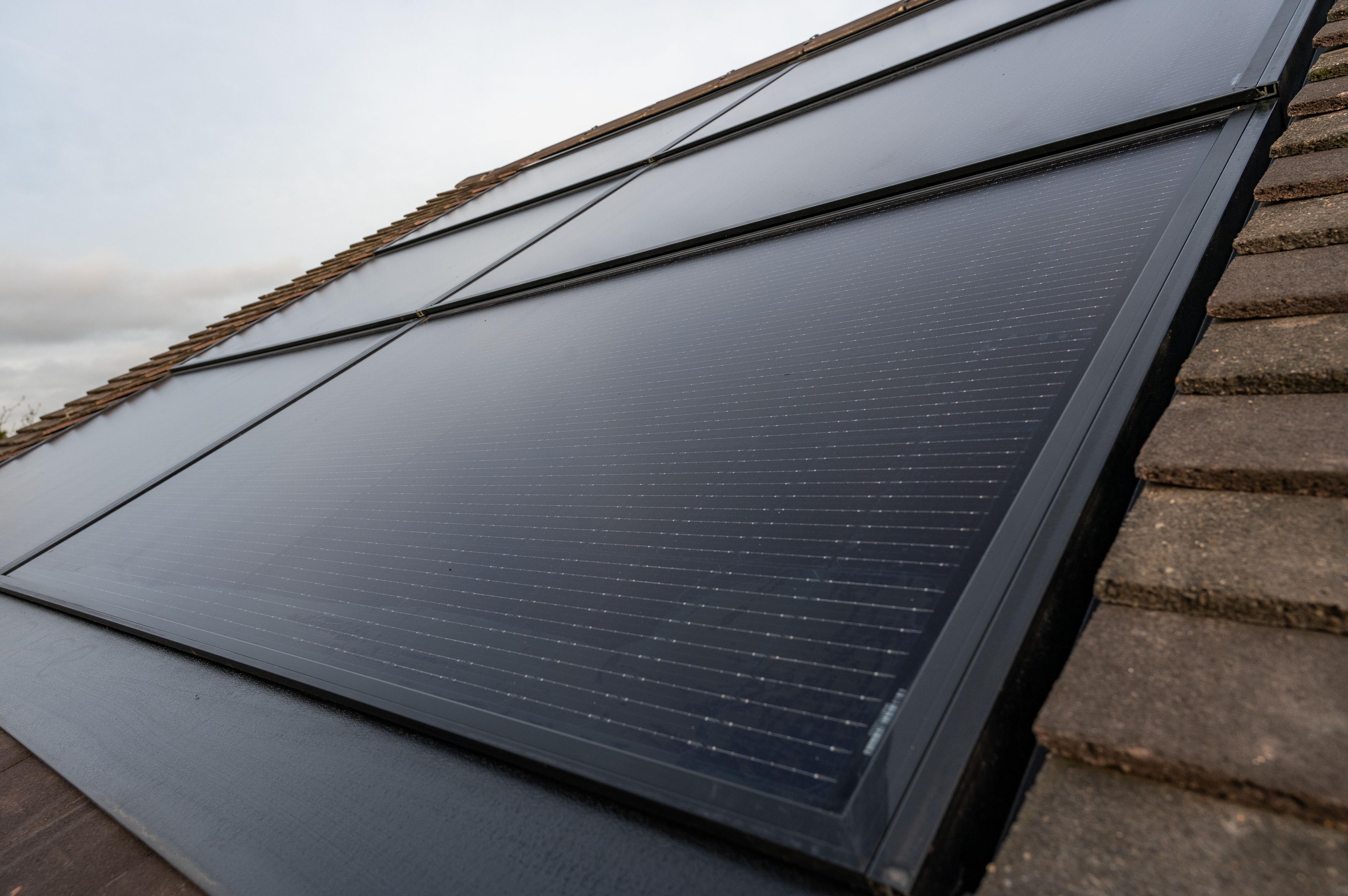 Close-up of black in-roof solar panels set flush into a tiled roof.