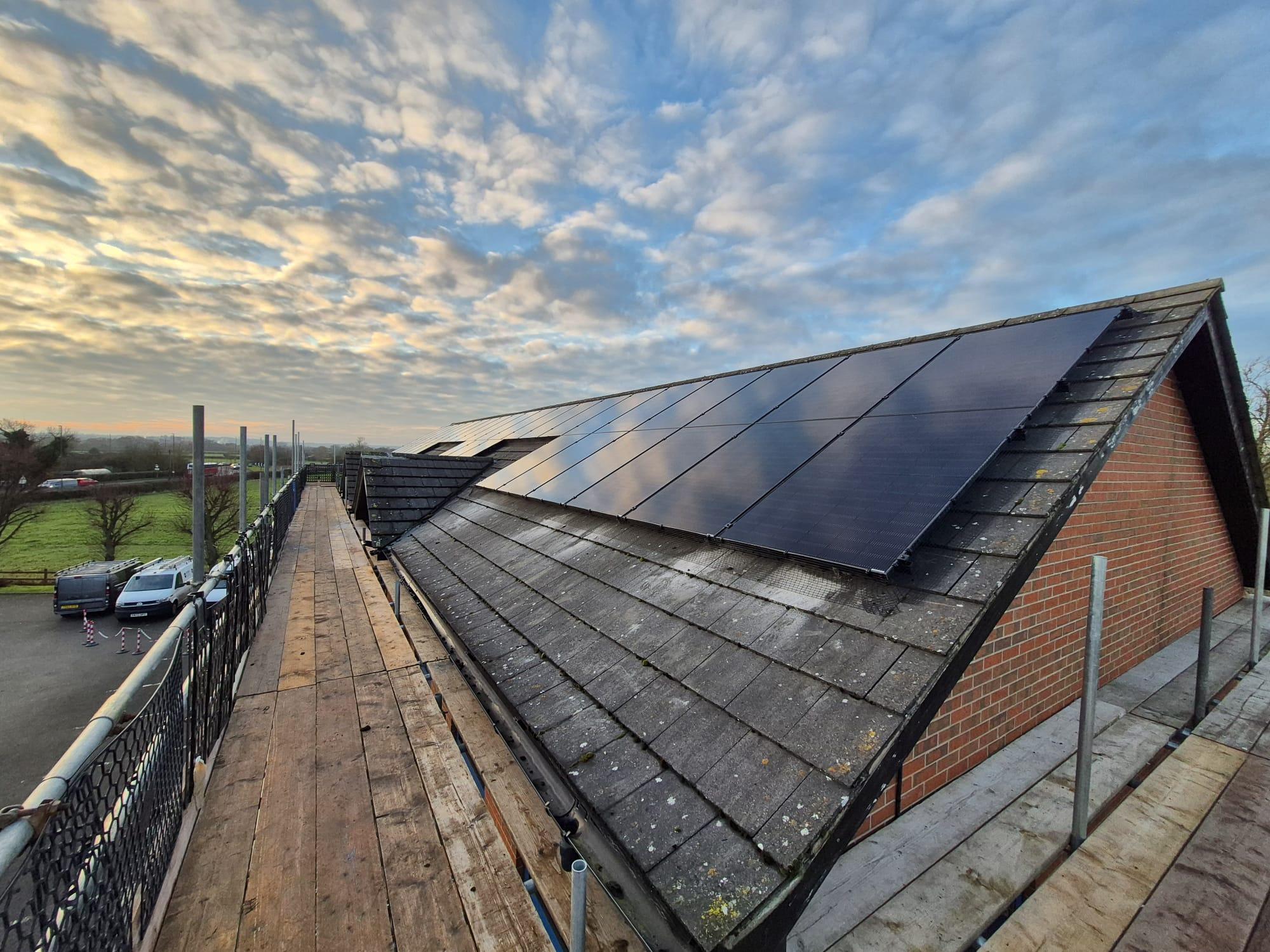 Black solar panels on the tiled roof of the Alpha Construction office, seen from the scaffold at sunrise.